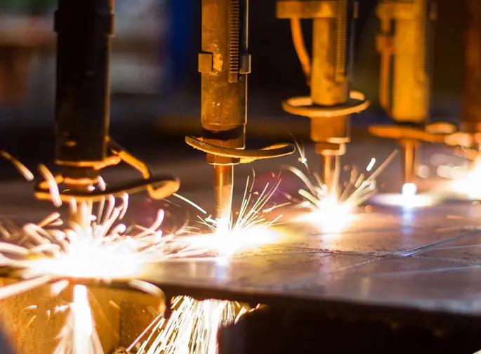 A group of people welding metal with bright sparks.