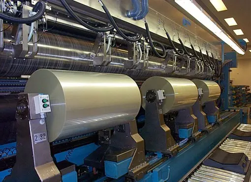 A machine that is in a factory with many rolls of paper.